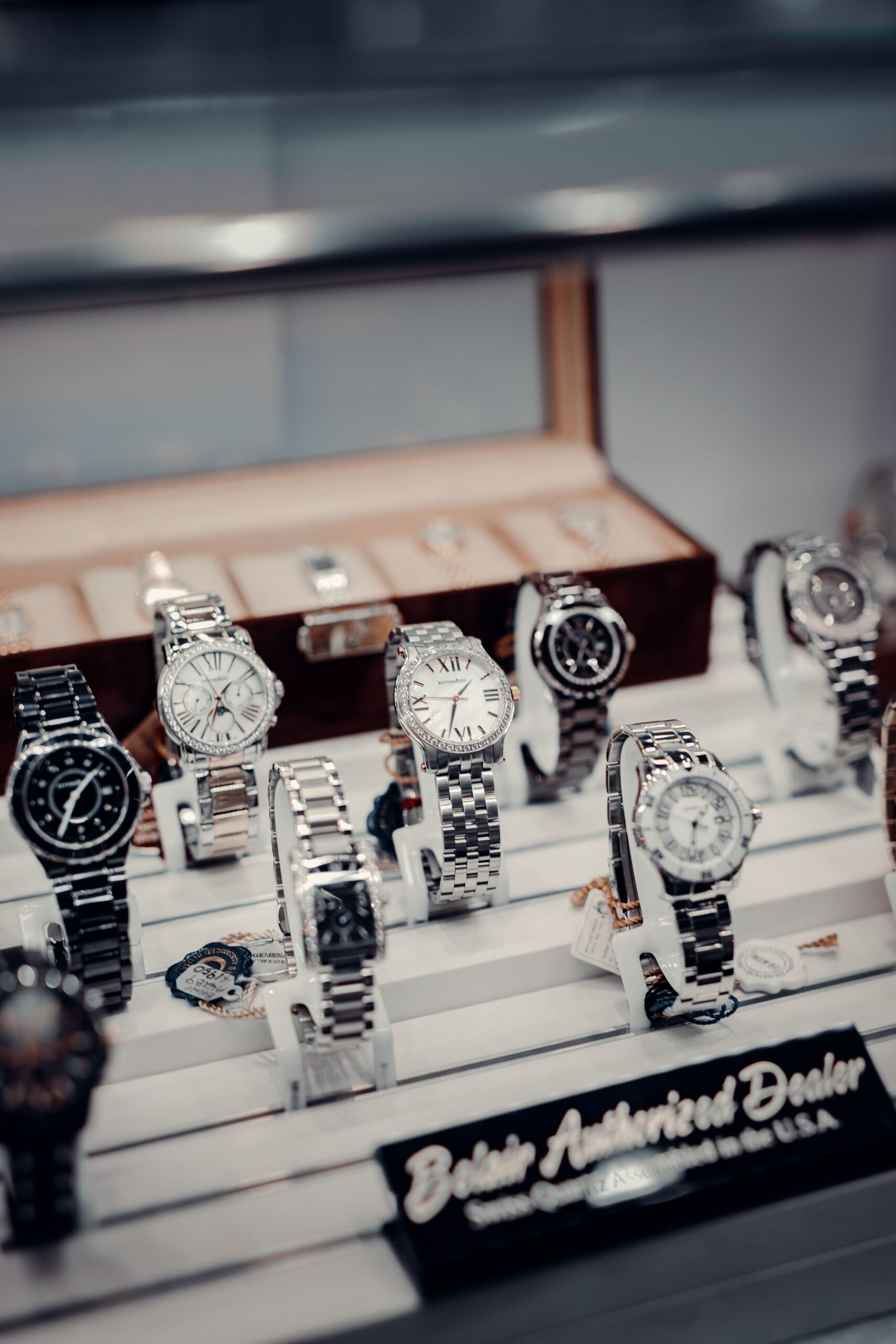 Collection of silver and black watches displayed in a jewelry store showcase.